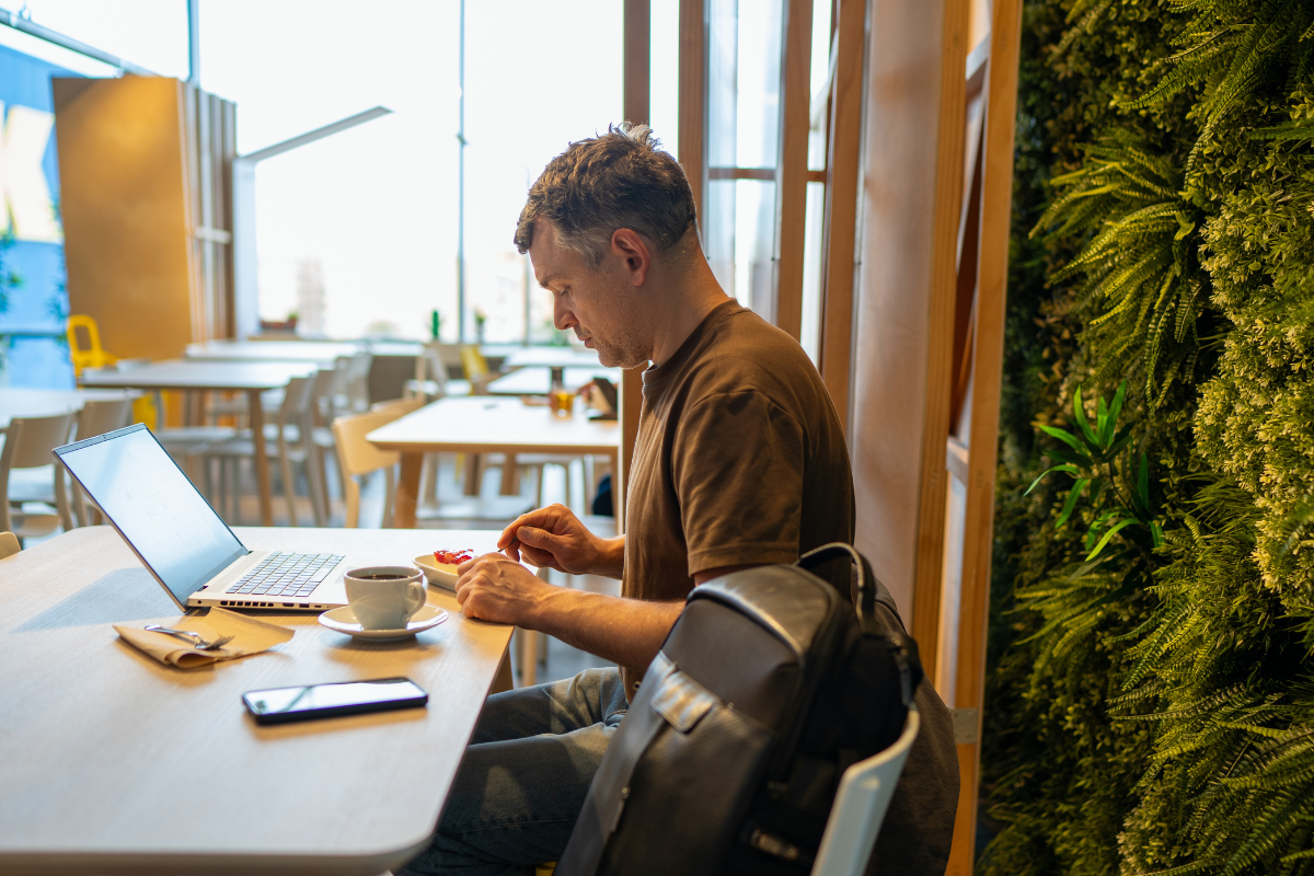 A man is working at a desk with a laptop and coffee cup..